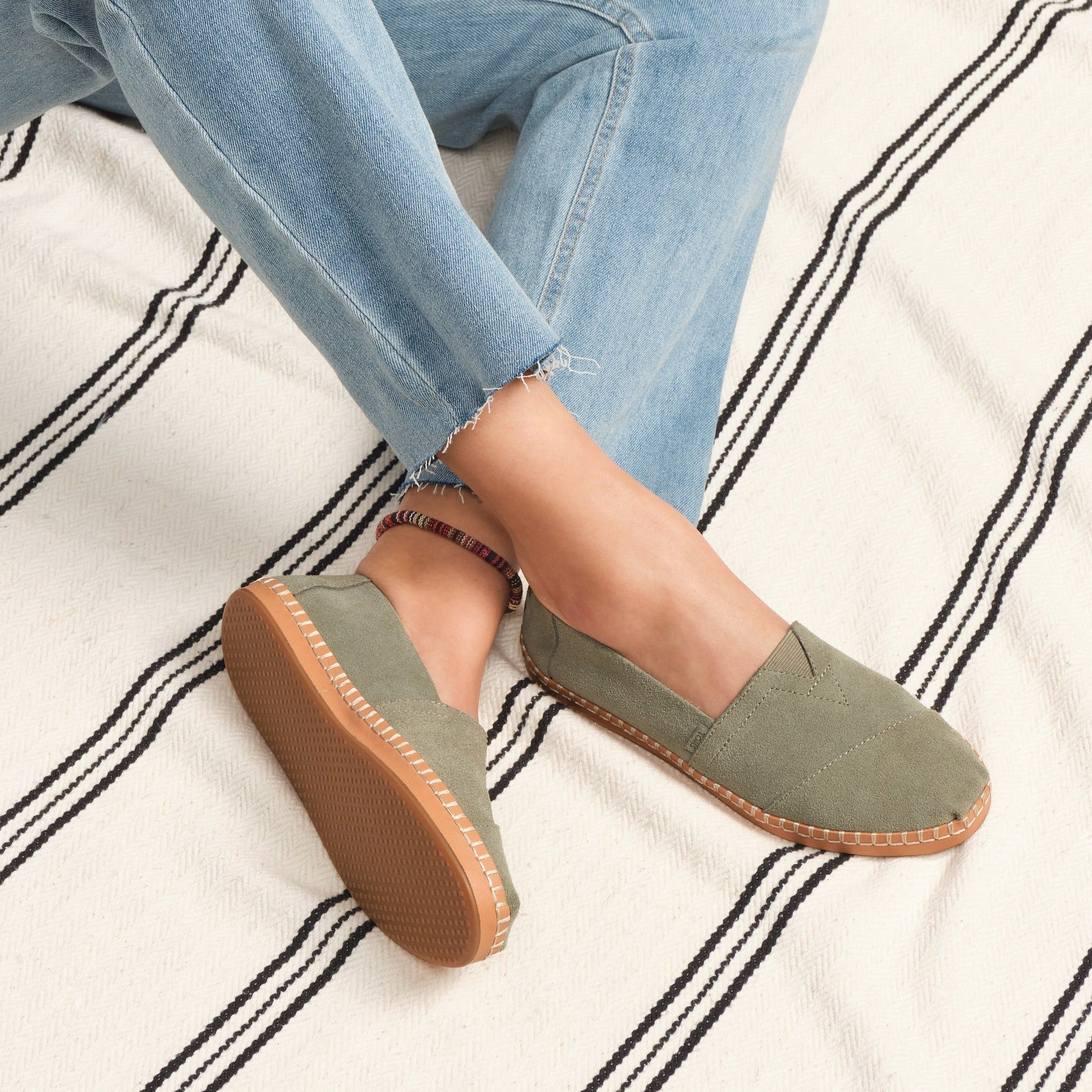 Leather Wrapped Alpargata In Sage Green Suede On Model Seated Wearing Jeans