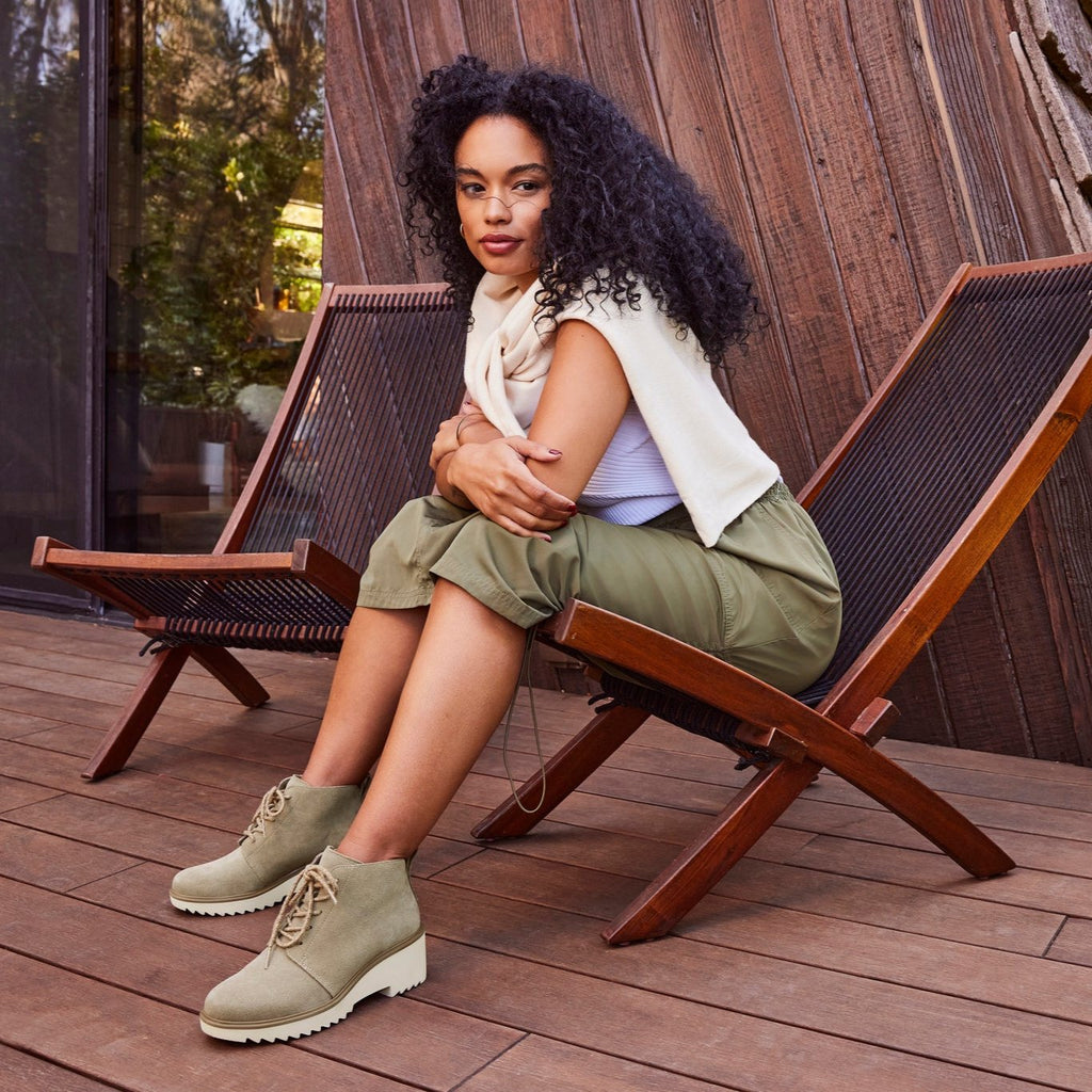 maude lace up boot in dune suede on model sitting on wooden deck