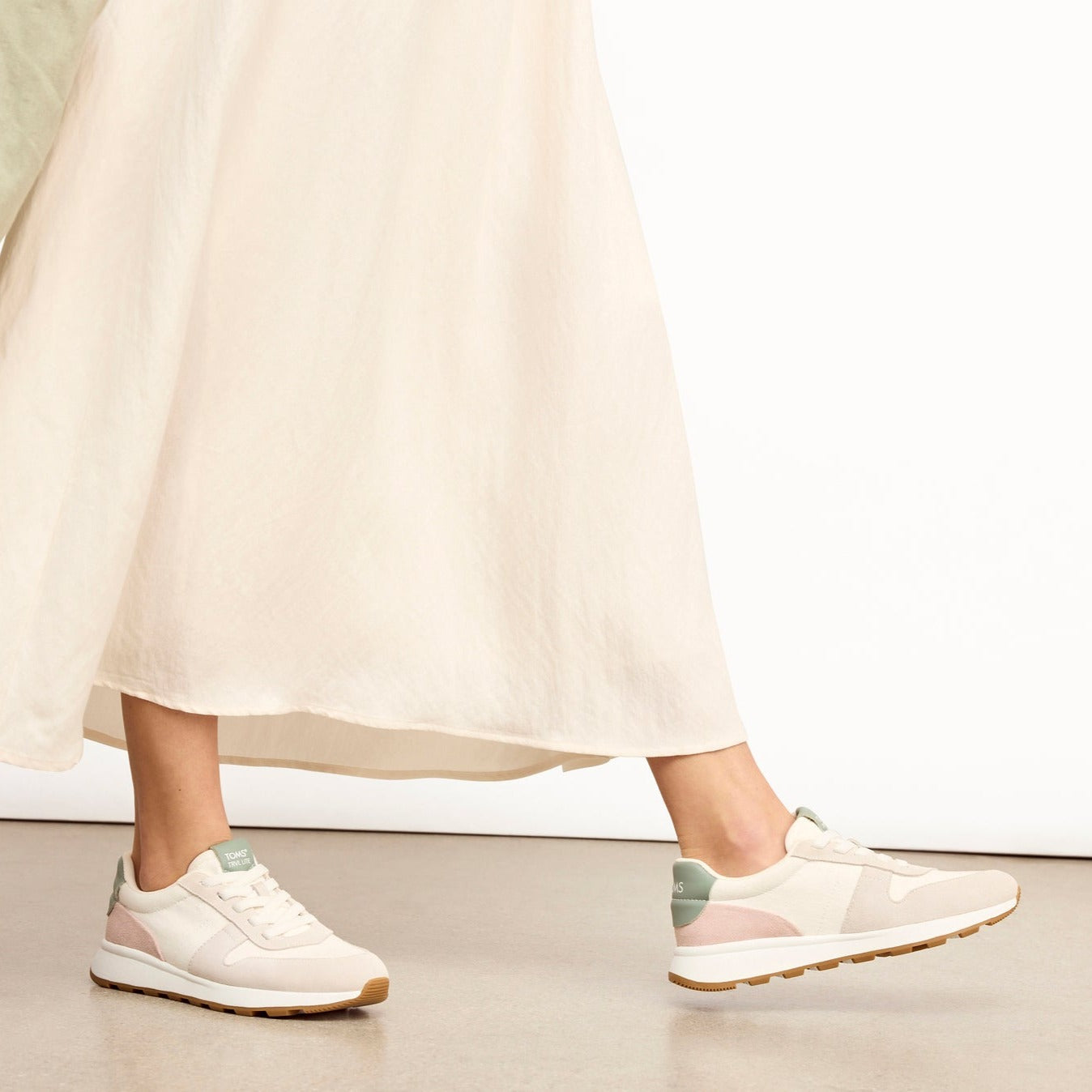 toms trvl lite retro runner on model walking wearing long cream skirt