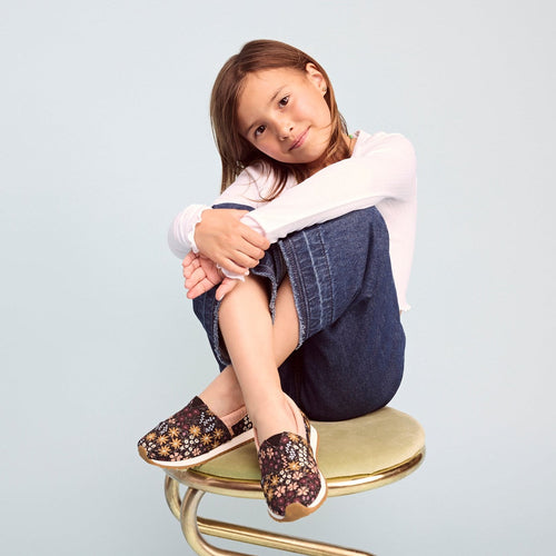 alpargata resident youth shoe on school age girl sitting on stool with detail shot of the floral pattern