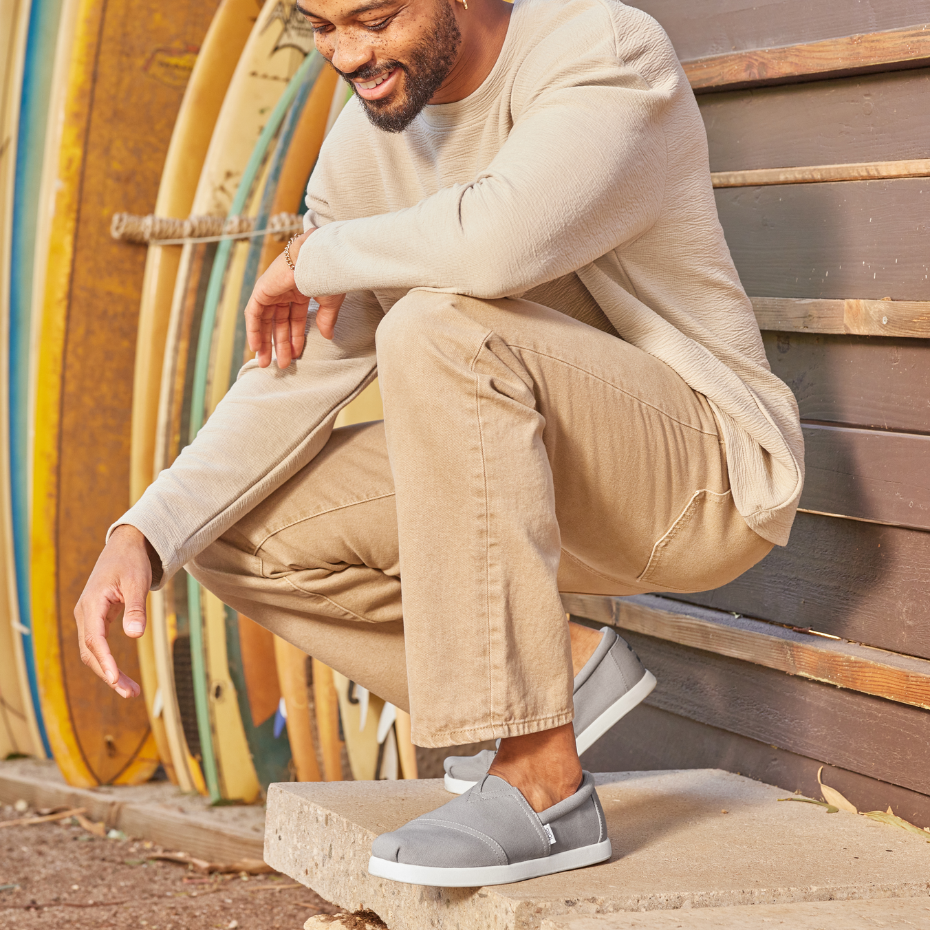 Mens Alpargata Fwd Slip On Casual Shoe In Grey On Model Squatting Next To Surf Boards