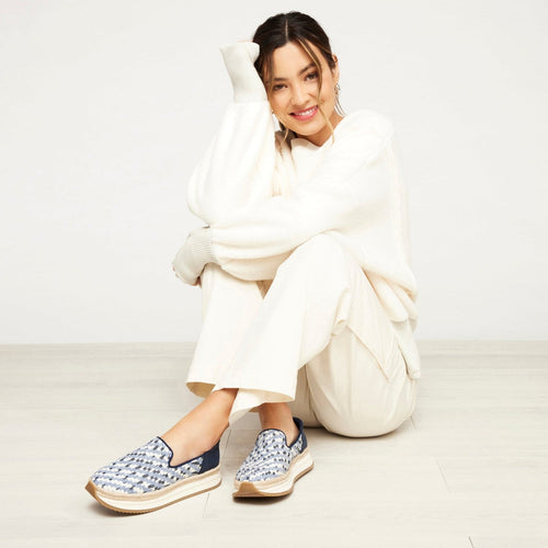 Jocelyn Sneaker In Cadet Blue On Model Wearing Cream Pants And Cream Sweater Sitting On Floor