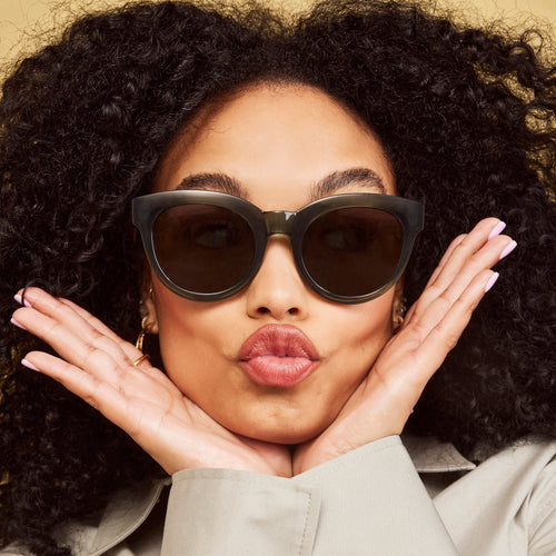 women's florentin traveler sunglasses in dark green frames with grey lenses up close on model detail shot